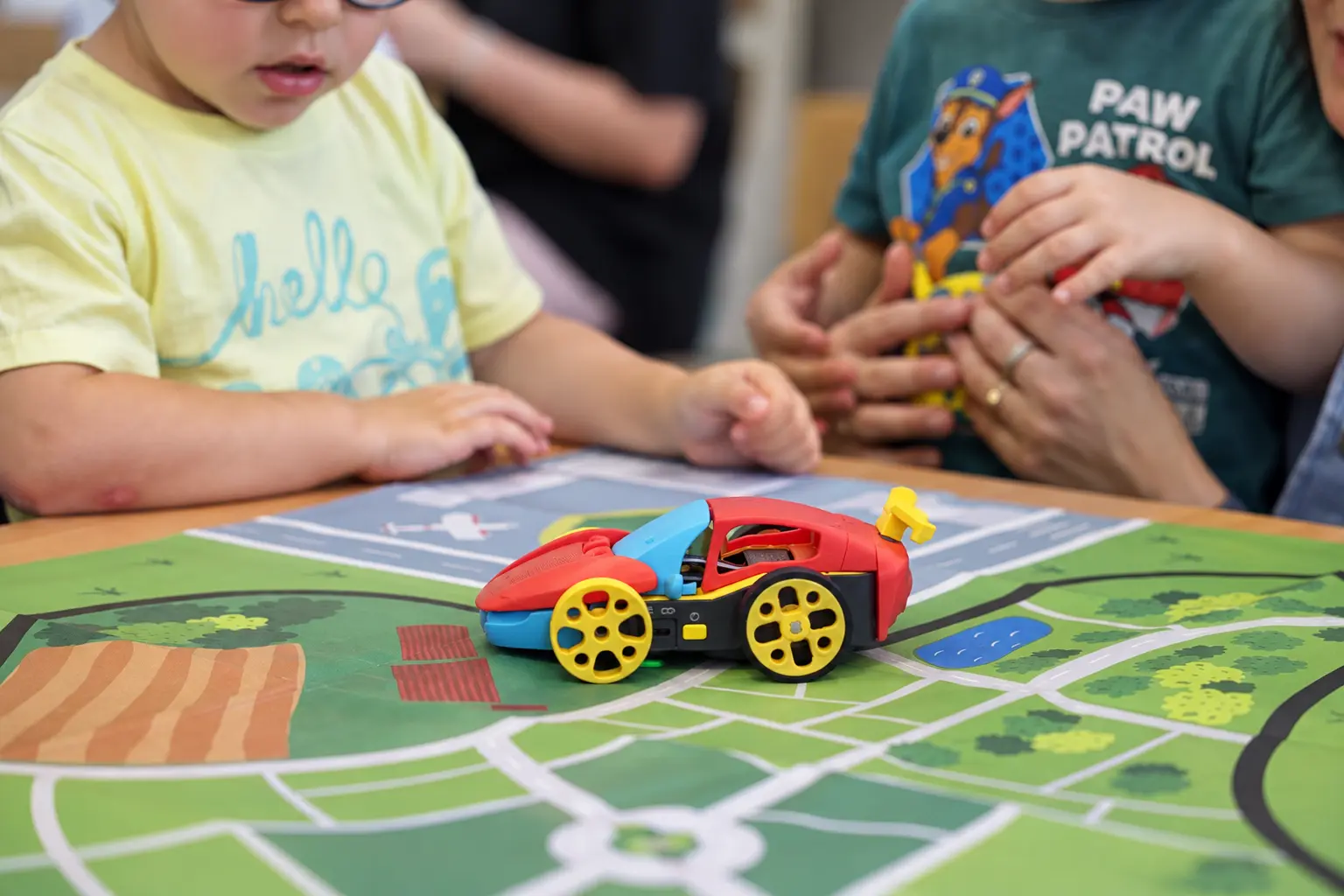 Dzieci składają kolorowe autko-robota na planszy z mapą