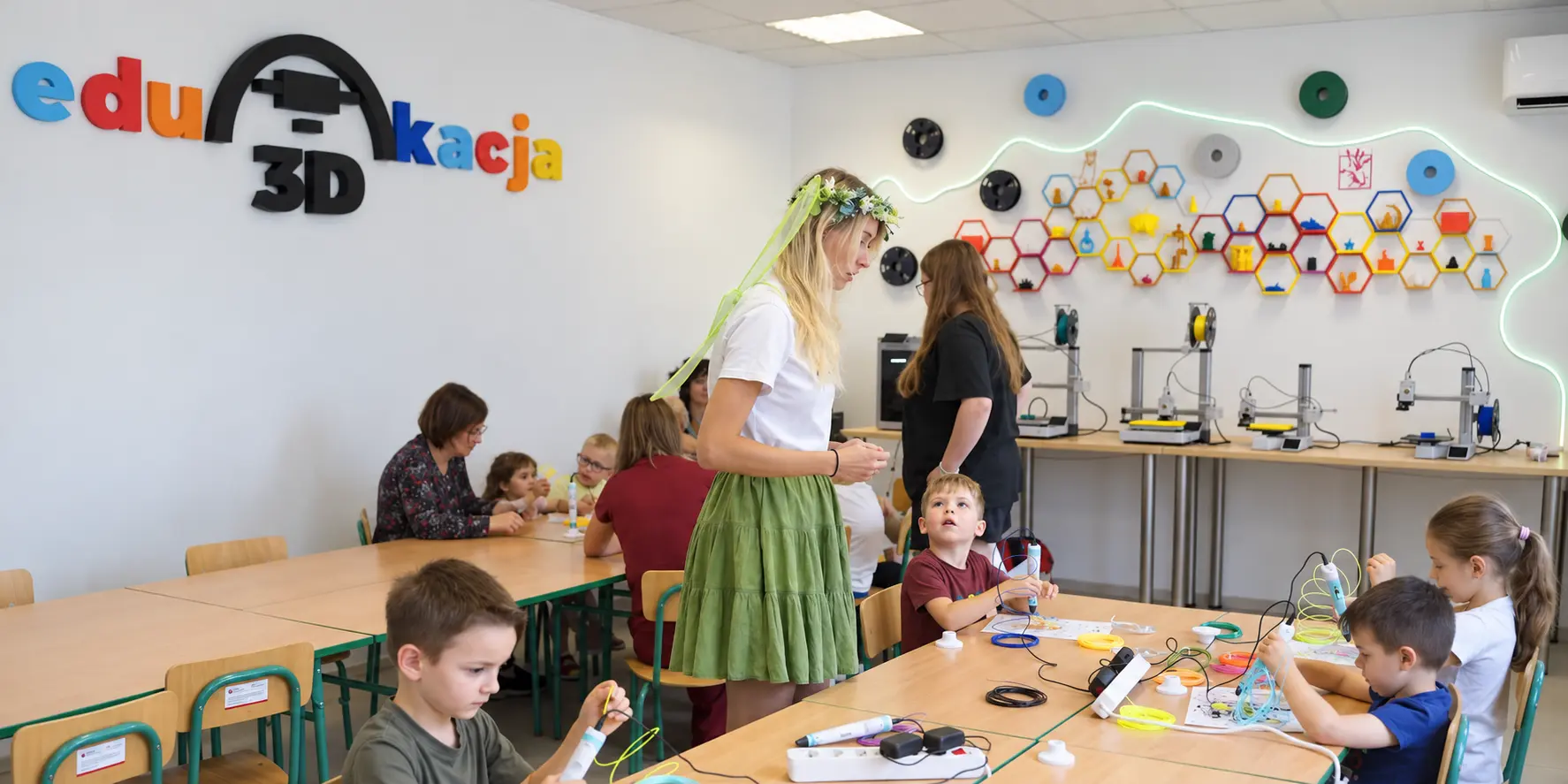 Sala zajęć Edu3Dkacja: dzieci i prowadząca przy stołach