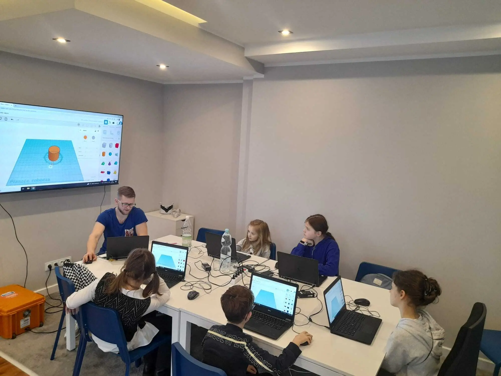 Prowadzący i dzieci przy laptopach z programem do projektowania 3D