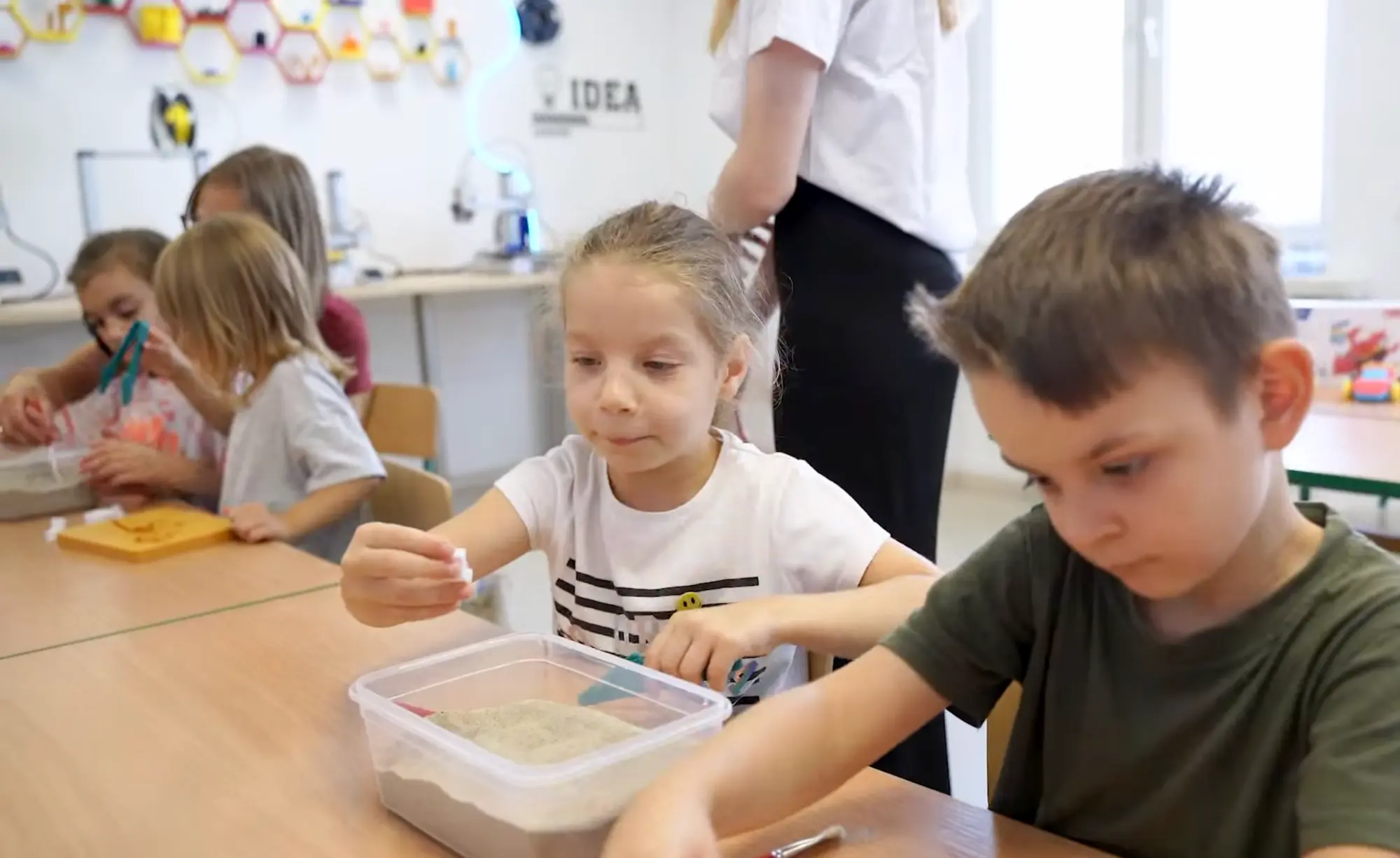 Dzieci przy stole podczas zajęć z drobnymi elementami