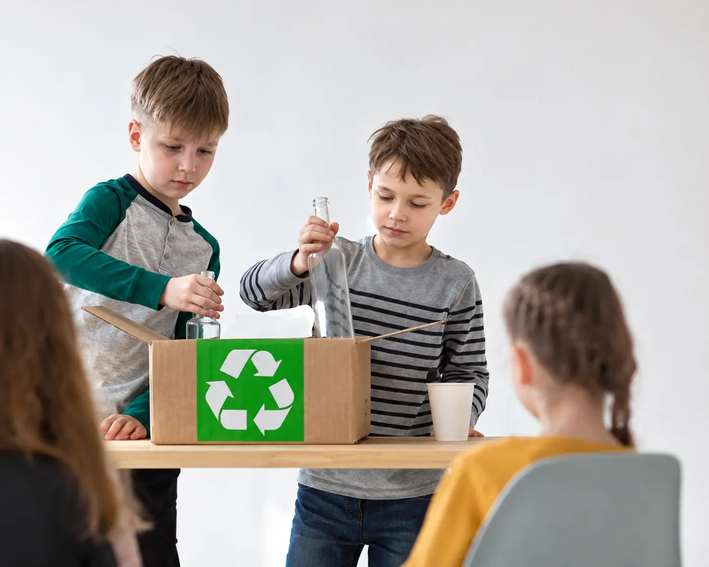 Chłopcy wrzucają odpady do pudełka z symbolem recyklingu