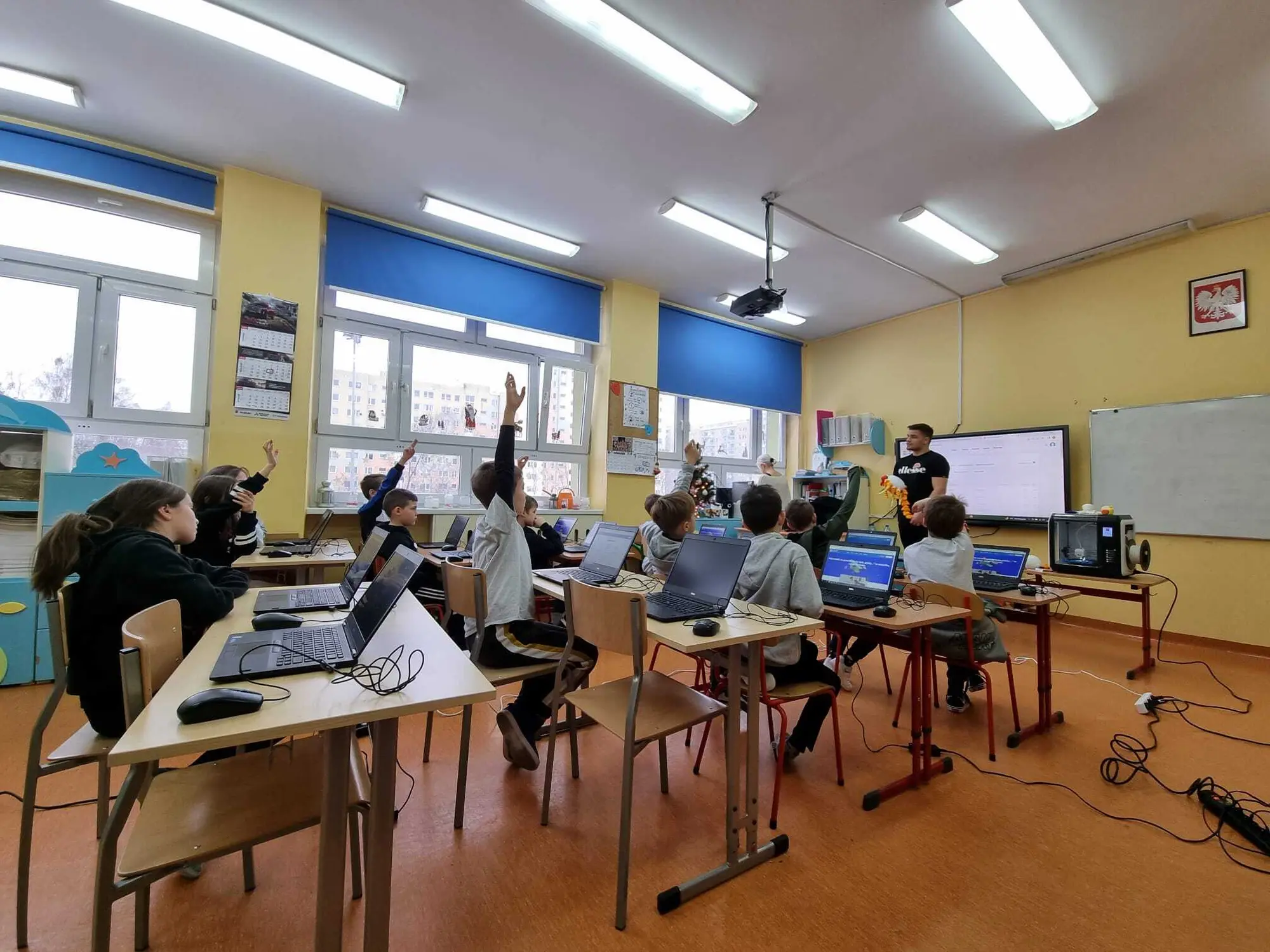 Uczniowie przy laptopach na zajęciach w sali lekcyjnej