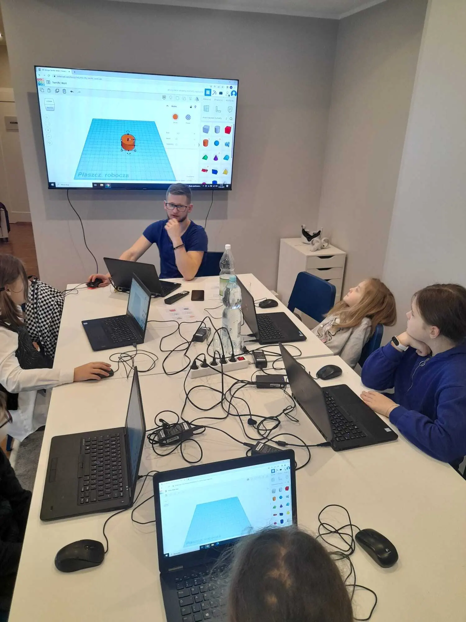 Dzieci przy laptopach na zajęciach z projektowania 3D, na ekranie model w programie